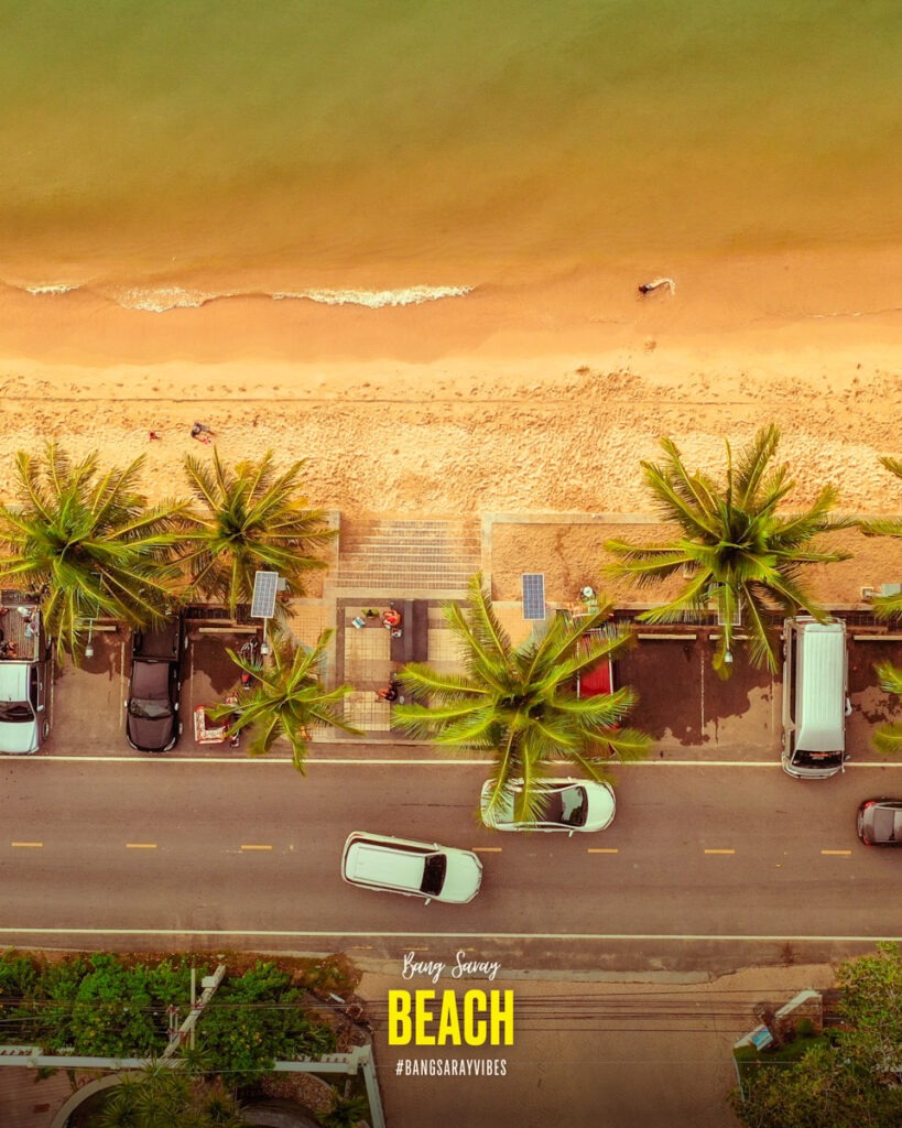 The image depicts a building with palm trees against a sunset backdrop at Bang Saray Beach. The scene captures a serene setting with a tropical vibe.